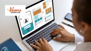 Team of web developers working on laptops and discussing website design in a modern office environment.